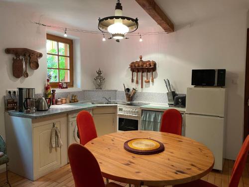eine Küche mit einem Holztisch mit roten Stühlen in der Unterkunft Ferienhaus im Haus der Künste in Rhodt unter Rietburg