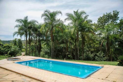 uma piscina azul com palmeiras ao fundo em Rancho Divino Espírito Santo- Beira Lago Corumbá IV em Alexânia
