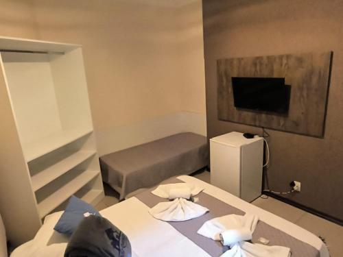 Habitación pequeña con 2 camas y TV. en Brotas Suítes Belo Quinto & Spazzio Bloco 2 en Brotas