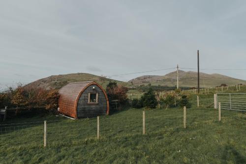 una pequeña cabaña en un campo con una valla en Sea View Pod Close to Mountains / Snowdonia en Caernarfon