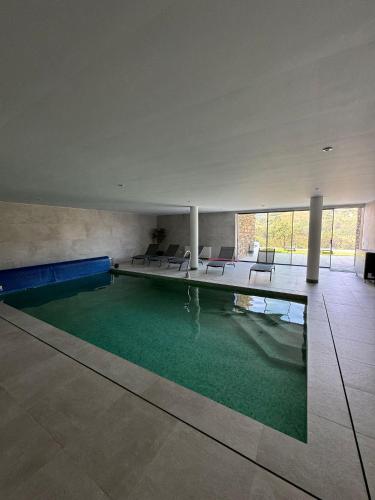 a large swimming pool in a building with chairs at Douro - Quinta das Manas - Baião in Alcarias