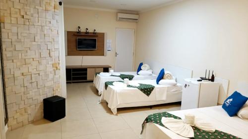 ブロタスにあるBrotas Suítes Belo Quinto & Spazzio Bloco 2のベッド3台とテレビが備わるホテルルームです。