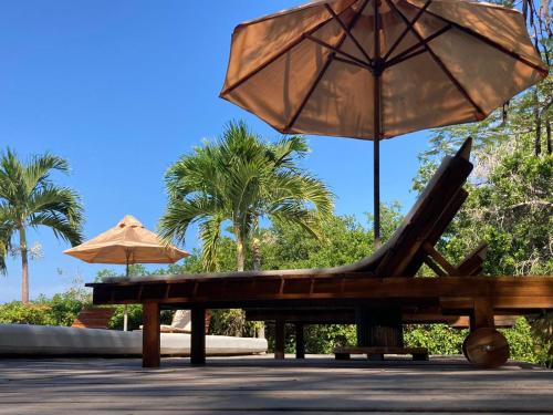 two umbrellas and a bench with a chair and umbrella at Hotel Playa Scondida Barú in Baru