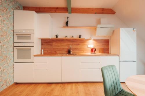 a kitchen with white cabinets and a green chair at Hviezdoslavova Apartments, Trnava Centre, Parking available in Trnava