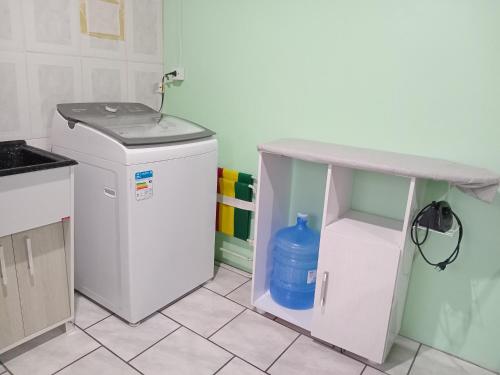 a washing machine in a kitchen with a table at Hospedaria das Azaleias in Novo Hamburgo