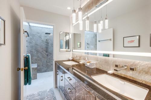 a bathroom with two sinks and two mirrors at Palm Springs Condo 3 Fenced Patios, Pool Access in Palm Springs