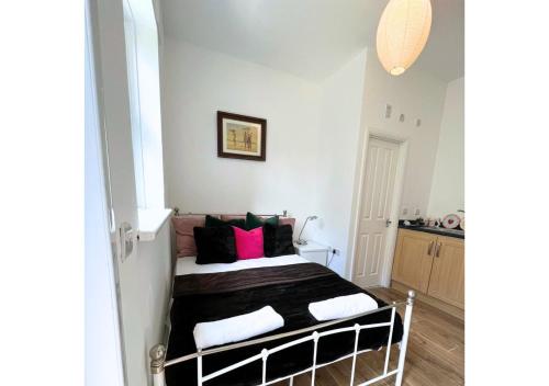 een slaapkamer met een bed met zwarte en roze kussens bij Cute Studio Garden Flat, 5 min to tube in Londen