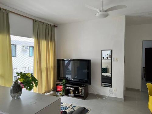 ein Wohnzimmer mit einem Flachbild-TV und einem Tisch in der Unterkunft Duplic Guaruja Enseada Apartamento in Guarujá