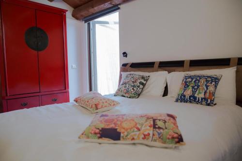 Cette chambre comprend un lit blanc avec des oreillers et une armoire rouge. dans l'établissement Mau House 44 Apartment, à Palerme