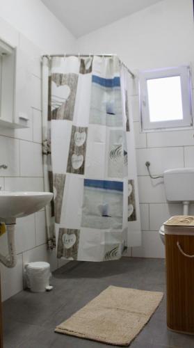 a bathroom with a shower curtain and a sink at Apartman Oliva in Posedarje