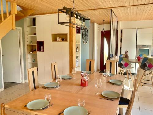 une table en bois avec des assiettes et des verres à vin dessus dans l'établissement Maison 180m2, jardin clos, 2 terrasses, 5 mn Dinan, à Vildé-Guingalan