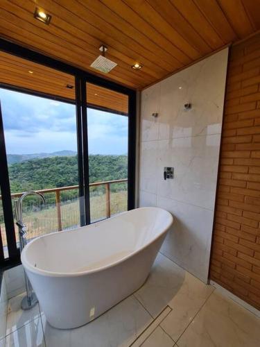 La salle de bains est pourvue d'une grande baignoire blanche et d'une fenêtre. dans l'établissement Castelinho Ibitipoca, à Lima Duarte