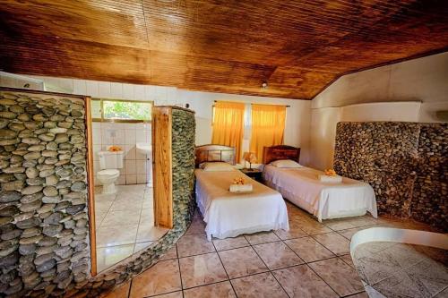 a bedroom with two beds and a stone wall at Hotel Chez Maria Goretti in Hanga Roa