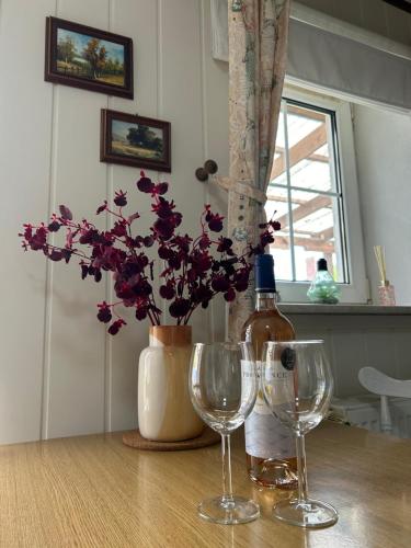 una mesa con dos copas de vino y un jarrón con flores púrpuras en Ferienwohnung ‘Storchennest’, en Tauche