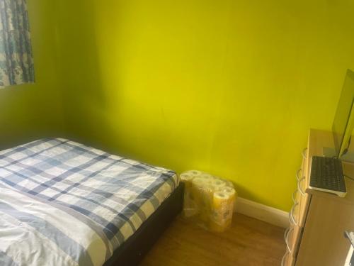 een slaapkamer met een bed en een gele muur bij Heathrow Terminal 5 in Staines upon Thames