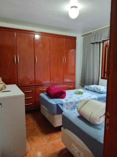 ノヴォ・アンブルゴにあるApartamento das Azaléias térreoのベッドルーム(ベッド2台、木製キャビネット付)
