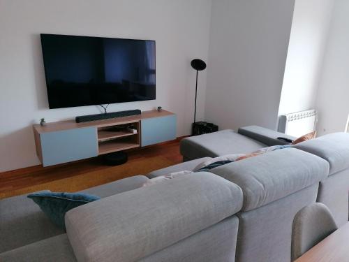 a living room with a couch and a flat screen tv at Dúplex Unquera. Piscina, garaje. in Unquera