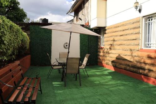 a patio with a table and chairs and an umbrella at U4RIC Villa-3bed house in Kileleshwa gated community in Nairobi
