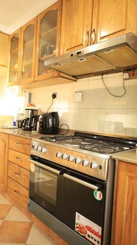 a kitchen with a stainless steel stove and wooden cabinets at U4RIC Villa-3bed house in Kileleshwa gated community in Nairobi