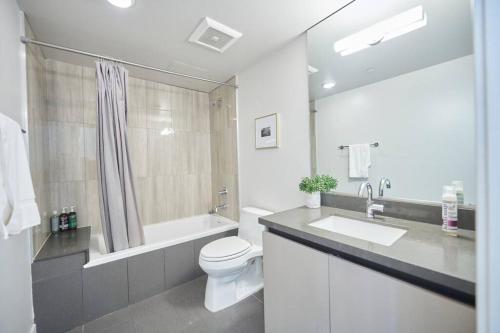 a white bathroom with a toilet and a sink at $3M Penthouse in K-Town with Private Roof Deck in Los Angeles