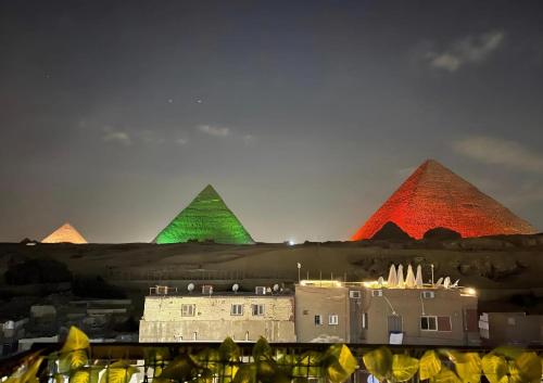 a group of pyramids lit up in red and green at Solima pyramids inn in Cairo