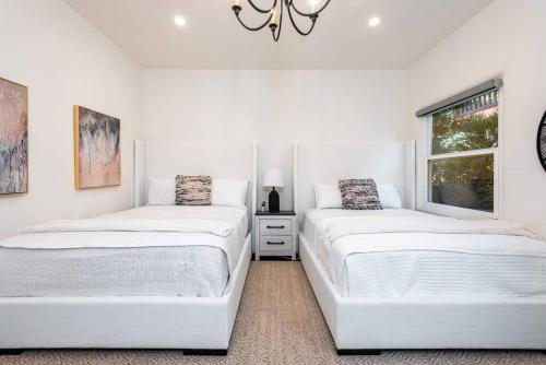 two beds in a white room with a window at Experience Luxury in a Spanish-Moroccan Escape in Los Angeles