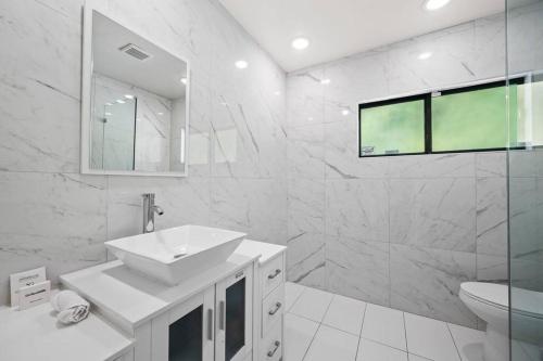 a white bathroom with a sink and a shower at Modern Luxe: 4BR Home with Private Jacuzzi in Los Angeles
