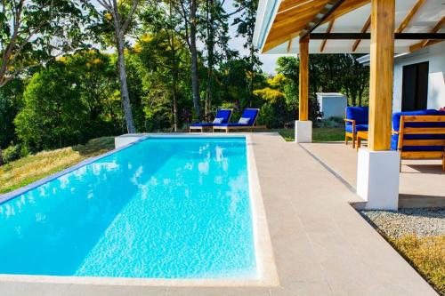 a swimming pool with blue chairs next to a house at Villa Saltamontes, ocean view and private pool! in Platanillo