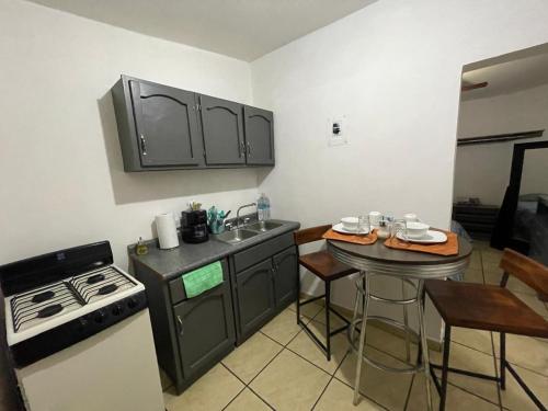 cocina con fogones, fregadero y mesa en Cozy studio apartment located in commercial area, en Hermosillo