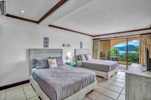 1 dormitorio con 2 camas y balcón en Newly remodeled unit in Flamingo with sweeping ocean views from big terrace, en Playa Flamingo