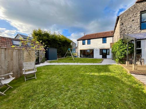 a yard with a bench and a house at Bi-Folds/Sonos/Large Open Plan/Central/Parking in Cheddar