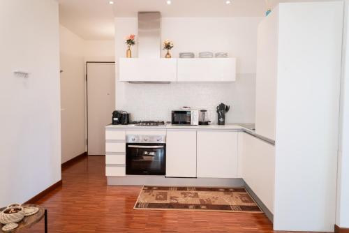 uma cozinha com armários brancos e um fogão em Ampio attico con terrazzo con vista, centrale, parcheggio gratis em Milano Marittima