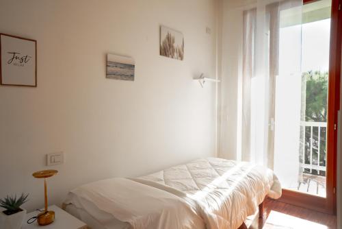 a white bedroom with a bed and a window at Attico panoramico, a pochi passi dal mare, due parcheggi interni inclusi in Milano Marittima