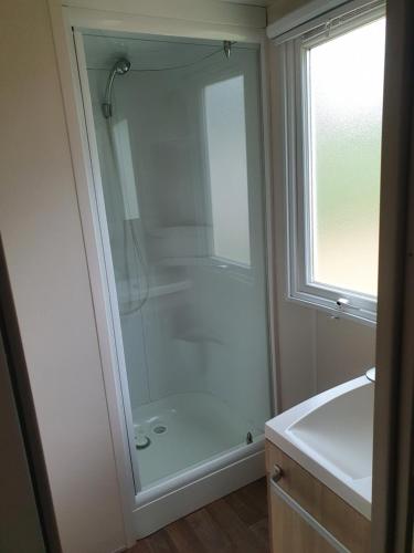 une salle de bain avec une douche avec une porte vitrée dans l'établissement Escale Douceur à Camiers, à Camiers