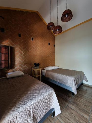 a bedroom with two beds and a brick wall at Central Hostel Boutique in Antigua Guatemala