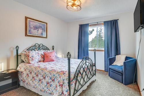 a bedroom with a bed and a blue chair and a window at Scenic and Serene Rapid City Getaway on 1 half Acres! in Rapid City