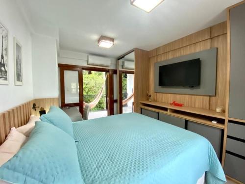 a bedroom with a blue bed and a flat screen tv at Villaggio dos Vinhedos in Bento Gonçalves