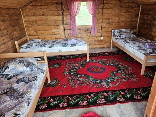 a room with three beds and a rug at Etno selo Raj na Uvcu in Sjenica