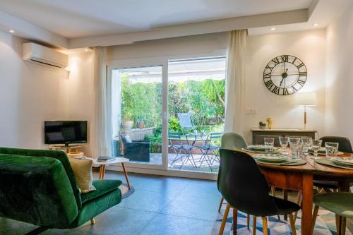 un salon avec une table, des chaises et une télévision dans l'établissement 1-Br Garden-level inside Upscale District, à Cannes