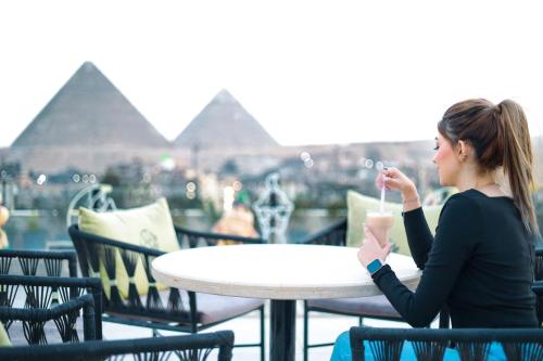 Una donna seduta a un tavolo a bere un drink di The Muse Pyramids INN a Il Cairo