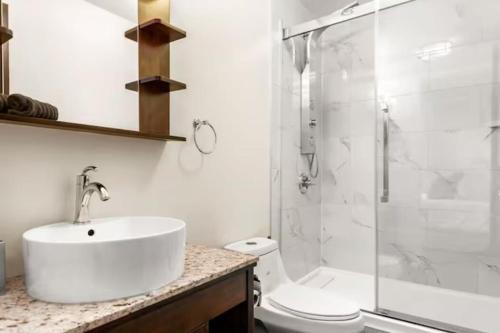 a white bathroom with a sink and a shower at Mt Lady MacDonald Suite @ Grande Rockies in Canmore