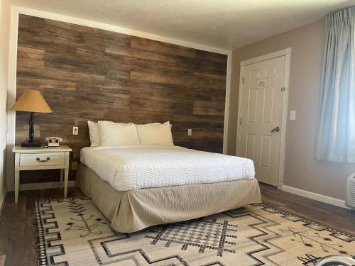 1 dormitorio con 1 cama y pared de madera en Mexican Hat Lodge, en Mexican Hat
