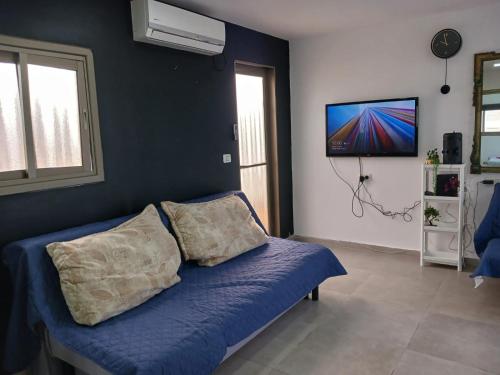 a living room with a blue couch and a flat screen tv at בלב העיר in Netanya