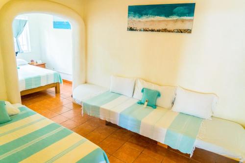 a room with two beds and a painting on the wall at Sayulita Central Hotel in Sayulita
