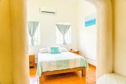 a bedroom with a bed and two windows at Sayulita Central Hotel in Sayulita