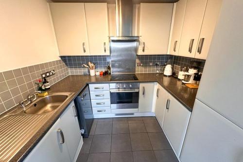 a kitchen with white cabinets and a sink at Trendy 1BD Penthouse wCity Views Hackney Wick in London