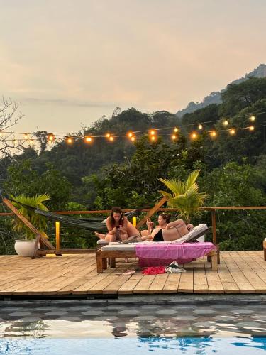 a group of people laying on a deck next to a pool at La Veranda Hotel & Restaurant in Minca