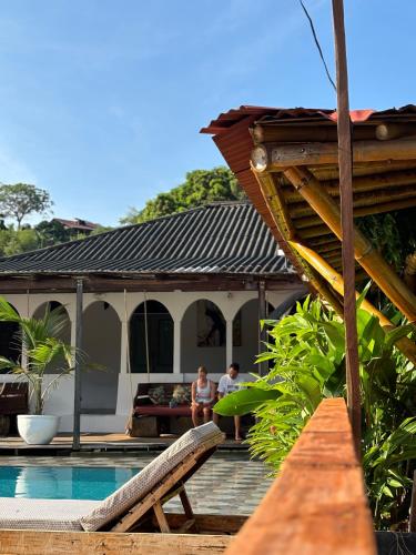 two people sitting on the deck of a house with a pool at La Veranda Hotel & Restaurant in Minca