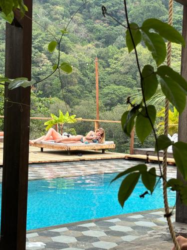a woman laying on a swing next to a swimming pool at La Veranda Hotel & Restaurant in Minca