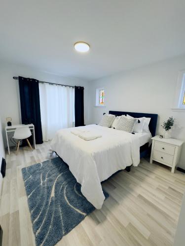 Schlafzimmer mit einem großen weißen Bett und einem blauen Teppich in der Unterkunft Walnut in Hamilton